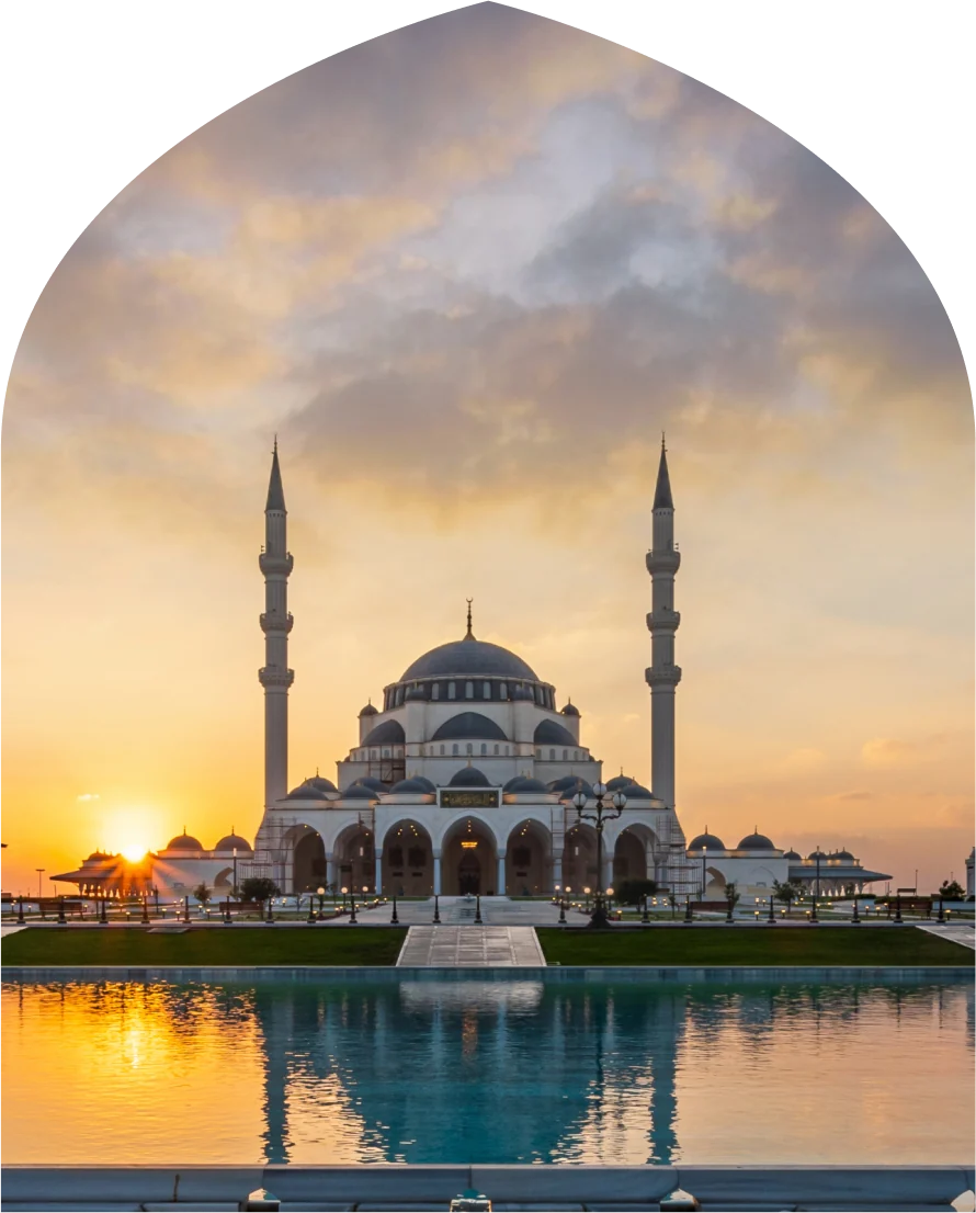 مسجد الشارقة عند الغروب، تنعكس قبابه ومآذنه على صفحة الماء أمامه